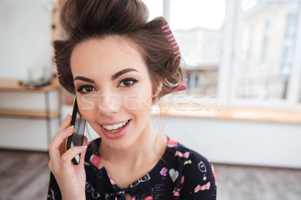 Cheerful woman in curlers talking on mobile phone Stock photo © deandrobot