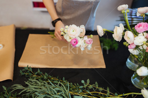 Hands of female florist creating bouquet on black table Stock photo © deandrobot