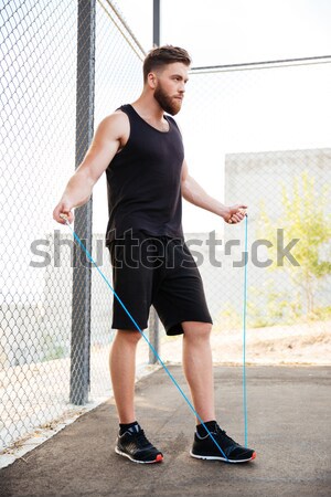 Souriant fitness homme séance jambes croisées pointant [[stock_photo]] © deandrobot