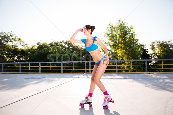 Woman in blue swimsuit riding on roller skates at park Stock photo © deandrobot