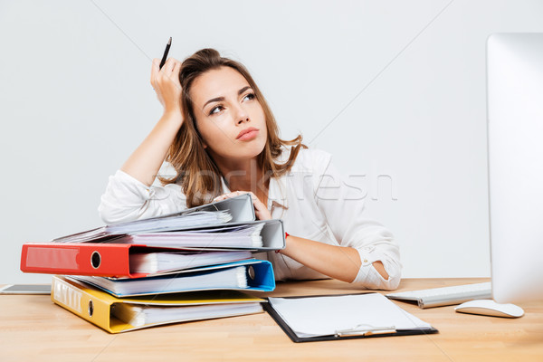 Pensive businessman sitting at the office desk and holding pen Stock photo © deandrobot