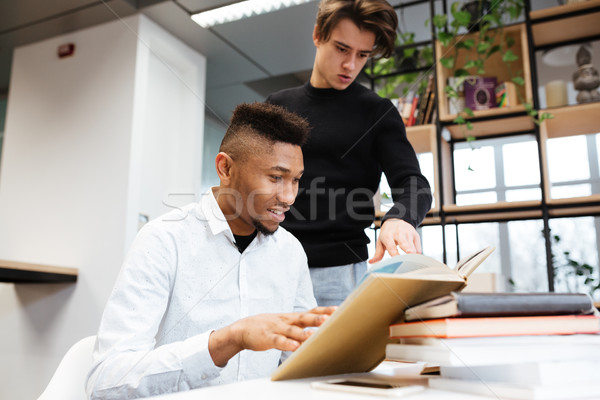 Two young handsome students in library learning education material Stock photo © deandrobot