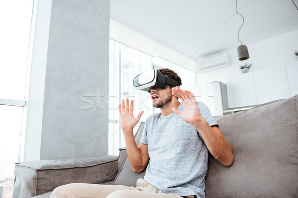 Shocked young man wearing virtual reality device Stock photo © deandrobot