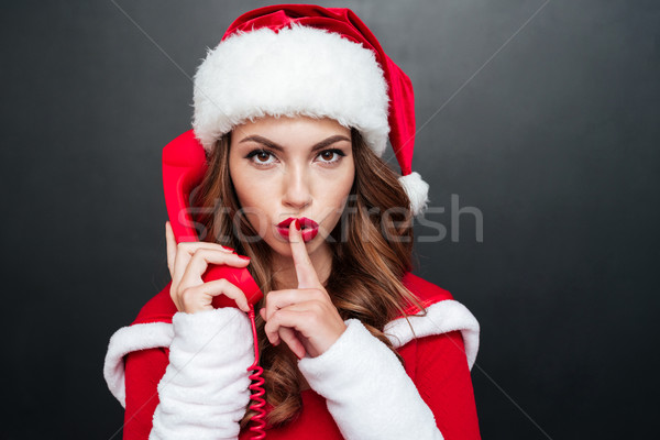 Woman in red santa claus hat showing silence gesture Stock photo © deandrobot