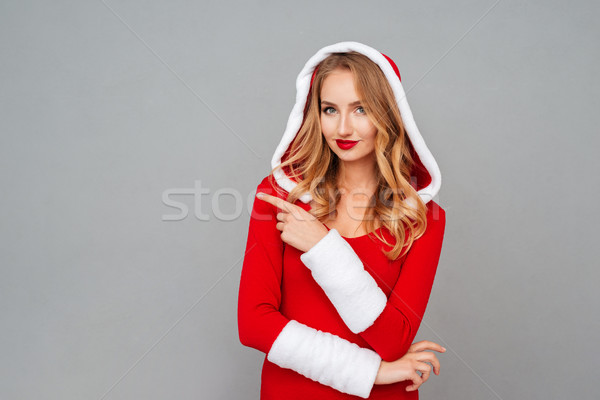 Smiling woman in New year dress with hood pointing away Stock photo © deandrobot