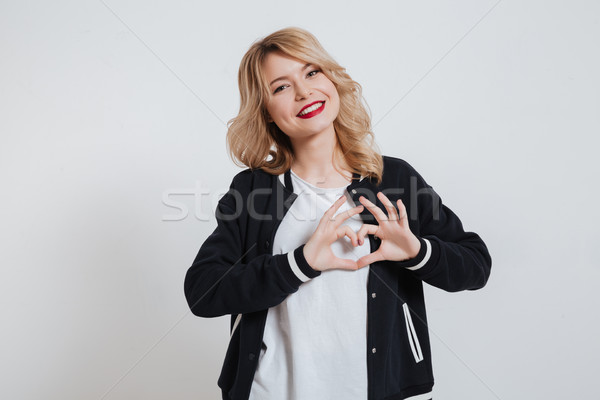 Cheerful girl in casual clothes making heart gesture with hands Stock photo © deandrobot
