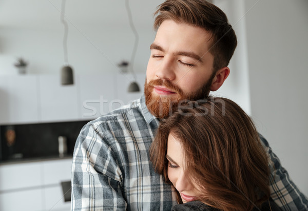 Happy loving couple hugging in kitchen at home indoors. Stock photo © deandrobot