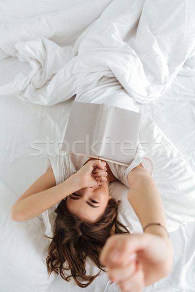 Stock photo: Incredible woman stretching and yawning while holding book.