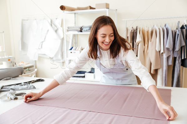 Woman seamstress spreading fabrics in workshop Stock photo © deandrobot