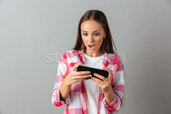 Photo of amazed pretty girl in checkered shirt, playing game on  Stock photo © deandrobot