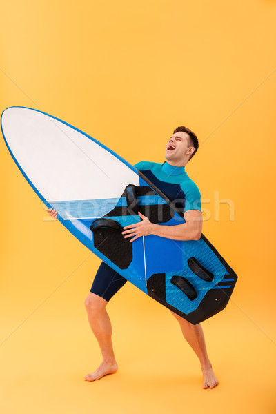 Full length portrait of funny man in swimsuit playing on surfboa Stock photo © deandrobot