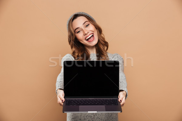 Cheerful brunette girl in winter clothes showing blank laptop co Stock photo © deandrobot