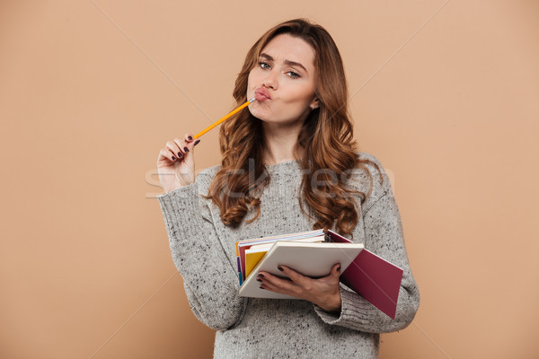 Young thinking woman with curly hairstyle standing while holding Stock photo © deandrobot
