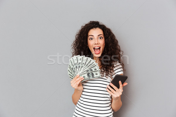 Portrait of woman in striped t-shirt holding fan of 100 dollar b Stock photo © deandrobot