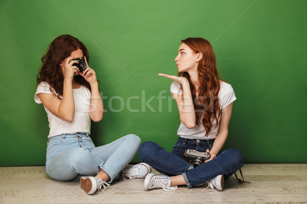 Photo of two redhead girls 20s sitting on floor with legs crosse Stock photo © deandrobot