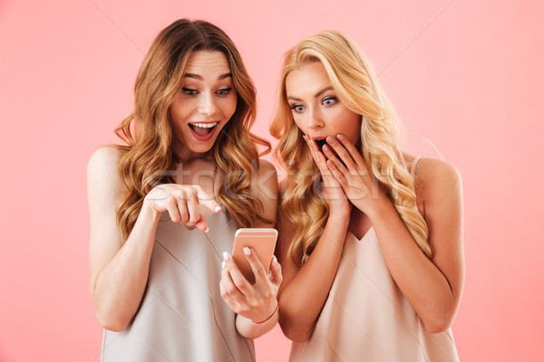 Two surprised pretty women in pajamas using together smartphone Stock photo © deandrobot