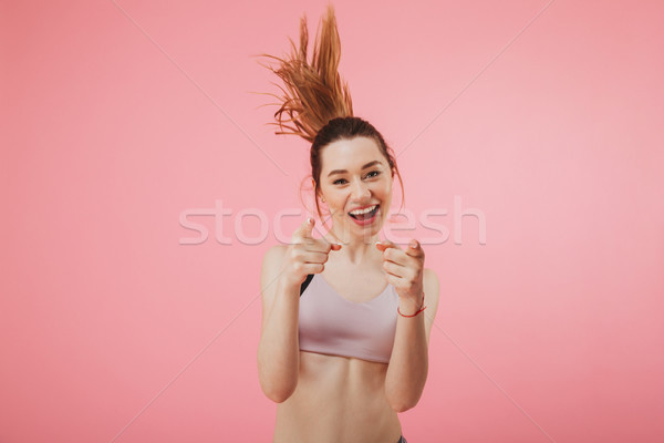 Smiling sportswoman running while pointing and looking at the camera Stock photo © deandrobot