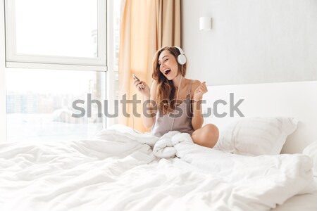 Stock photo: Portrait of a cheerful woman with raised hads up on the bed