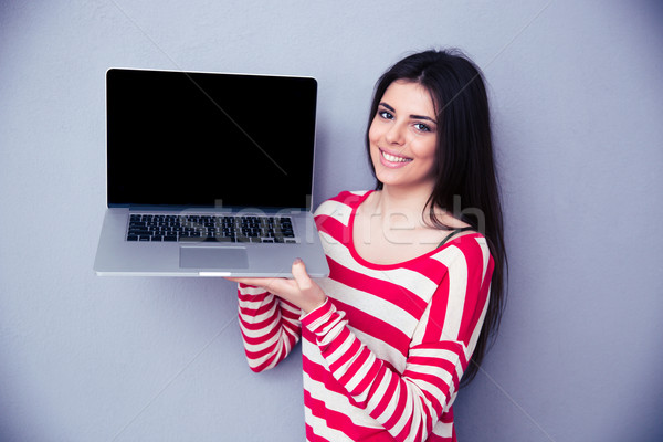 Femeie zambitoare laptop afişa gri uita Imagine de stoc © deandrobot