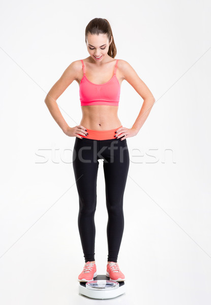 Lovely sportswoman standing on weighing scale and looking down Stock photo © deandrobot