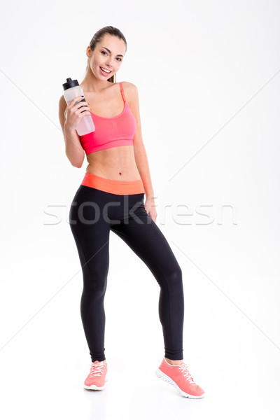 Positive beautiful young sportswoman with bottle of water  Stock photo © deandrobot