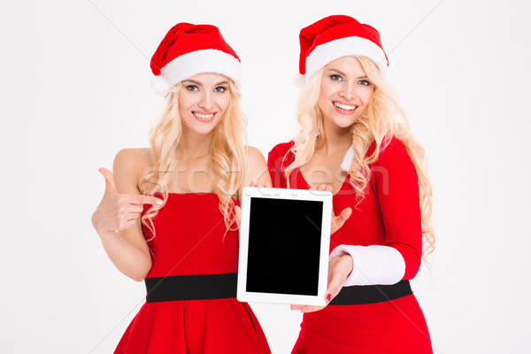 Stock photo: Smiling women in santa cloth showing tablet computer screen