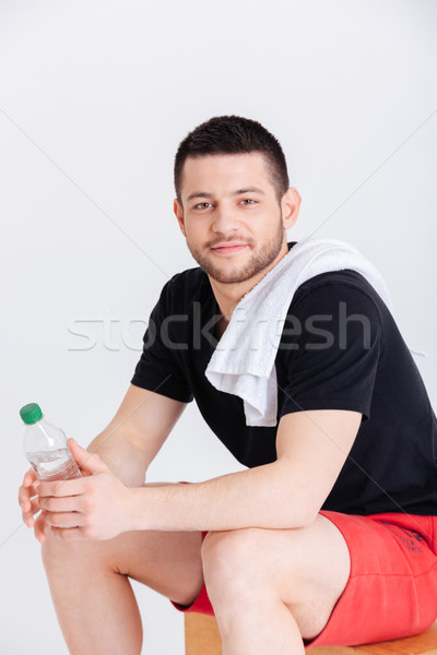 Sports man holding bottle with water and looking at camera Stock photo © deandrobot