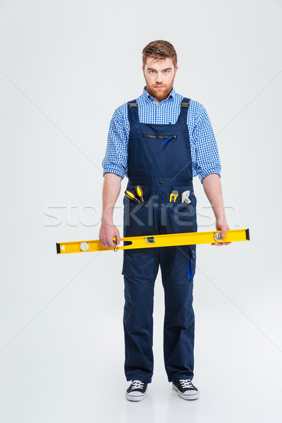 Serious male builder holding waterpas Stock photo © deandrobot