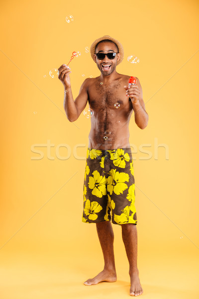 Cheerful man in swim wear having fun with soap bubbles Stock photo © deandrobot