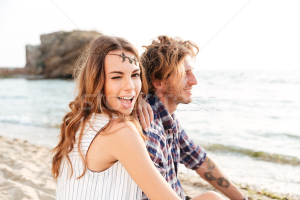 Couple sitting and winking on the beach Stock photo © deandrobot