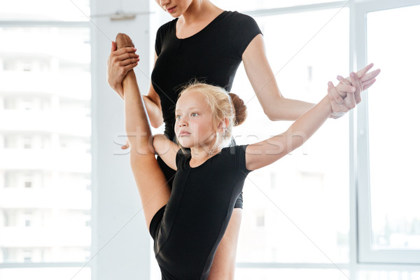 Little balerina stretching legs with her teacher in ballet studio Stock photo © deandrobot