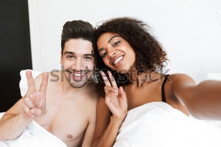 Young interracial couple in bed Stock photo © deandrobot