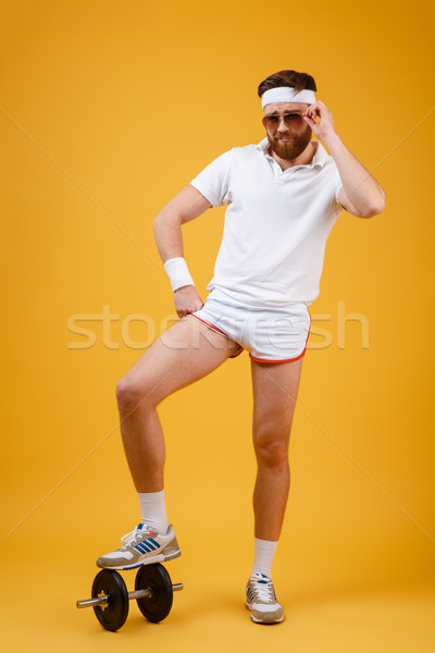 Vertical image sportsman standing on dumbbell holding arm at hip Stock photo © deandrobot