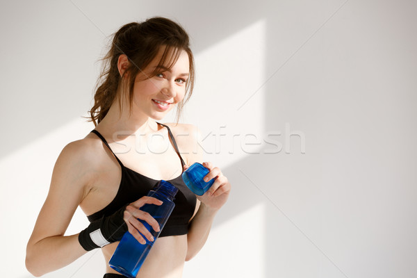 Cheerful young sports woman boxer drinking water. Stock photo © deandrobot
