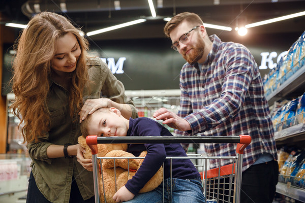 Young boy sitting in shopping trolley in supermarket Stock photo © deandrobot
