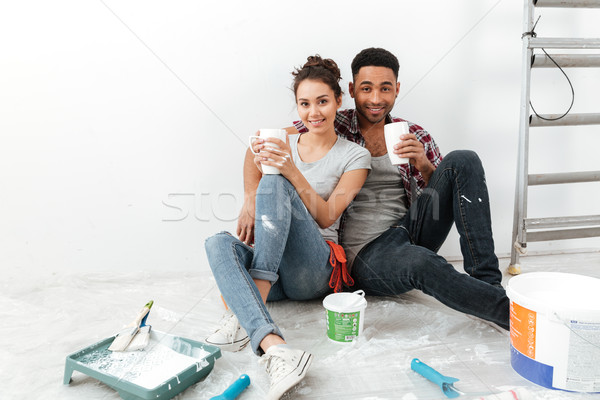 Happy beautiful young couple drinking coffee and renovating home Stock photo © deandrobot