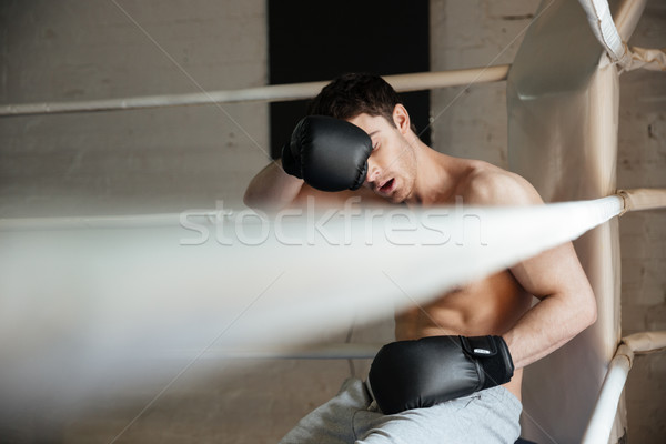 Tired boxer wiping the sweat while sitting on ring Stock photo © deandrobot