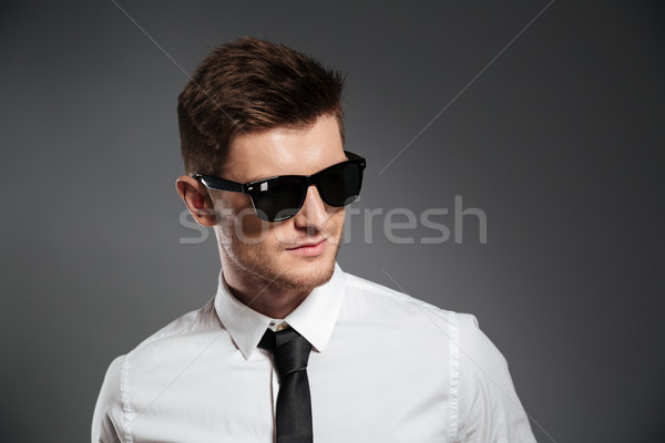 Portrait of a stylish young man in sunglasses looking away Stock photo © deandrobot