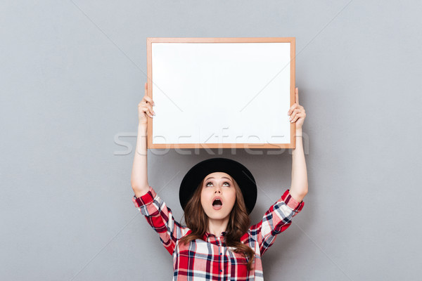 Shocked young lady standing over grey background Stock photo © deandrobot