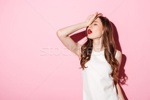 Stock photo: Portrait of annoyed beautiful woman placing back hand on forehead