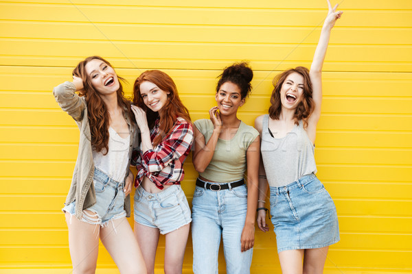 Sonriendo mujeres amigos pie amarillo pared Foto stock © deandrobot