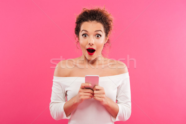 Portrait of a happy excited girl holding mobile phone Stock photo © deandrobot