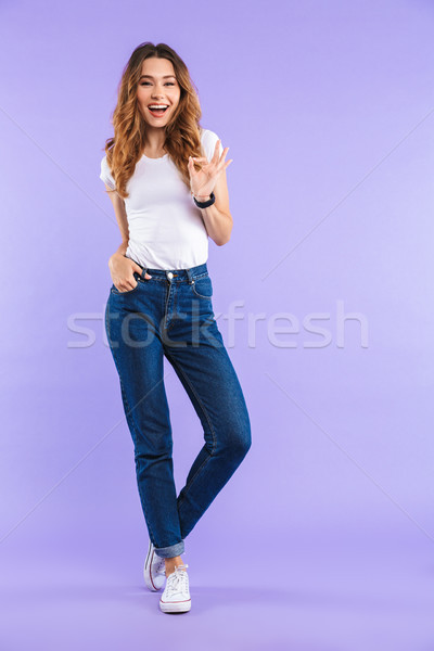 Happy cute woman isolated over purple wall background showing okay gesture. Stock photo © deandrobot