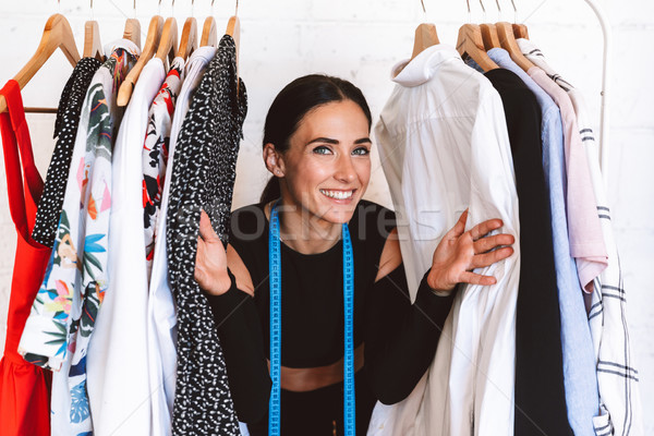 Derűs fiatal nő ruházat designer áll ruhaakasztó Stock fotó © deandrobot