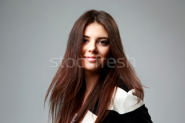 Stock photo: Studio shot of a young smiling woman in casual clothes on gray background