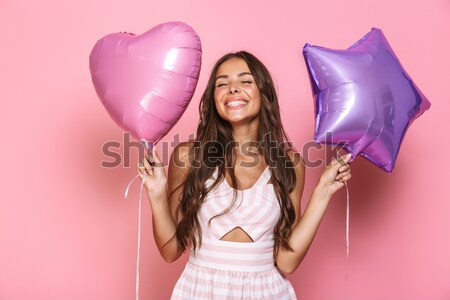 Smiling woman covering her eye with heart shaped balloon Stock photo © deandrobot