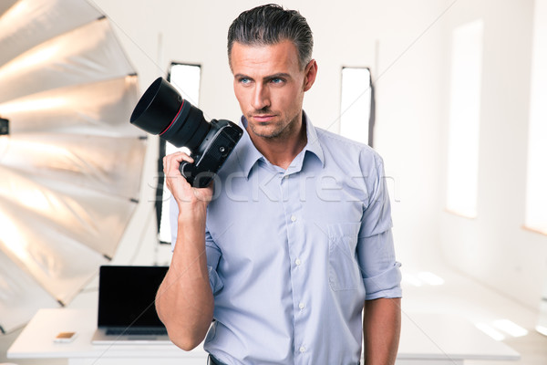 Serious photographer holding camera Stock photo © deandrobot