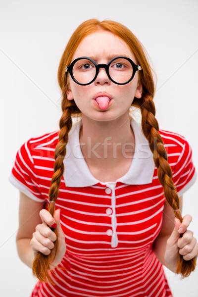 Funny amusing girl in round glasses showing tongue  Stock photo © deandrobot