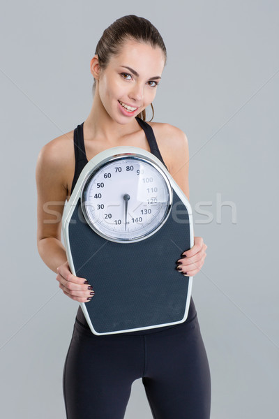 Portrait of happy fitness girl in sportwear with weigh scale  Stock photo © deandrobot