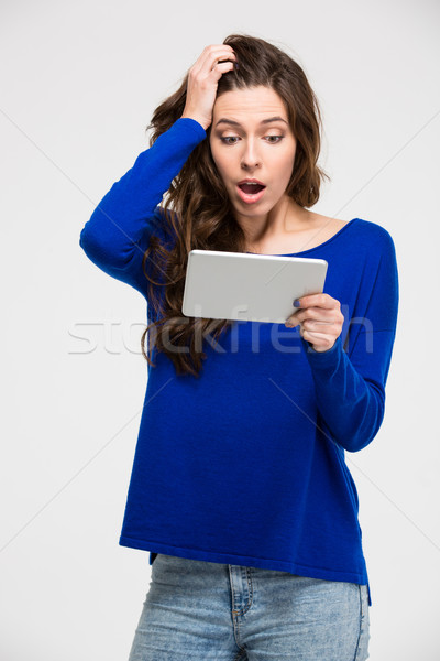 Stock photo: Amazed woman using tablet computer 